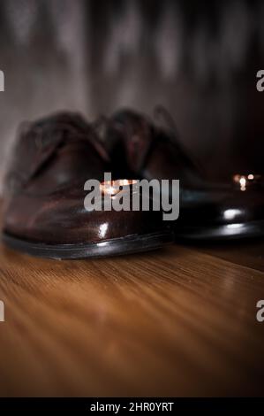 Lederschuhe für Herren, ein Paar goldene Eheringe in einer Holzkiste. Accessoires des Bräutigams Stockfoto