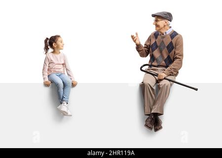 Großvater sitzt auf einer leeren Tafel und spricht mit einem kleinen Mädchen isoliert auf weißem Hintergrund Stockfoto