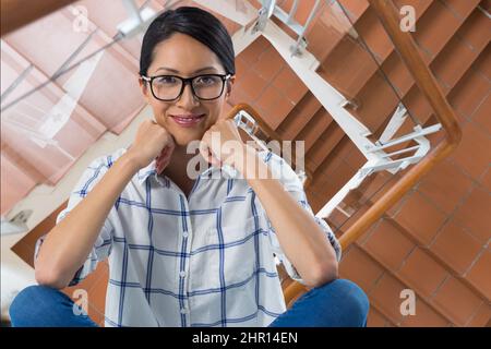 Zusammengesetztes Bild des Porträts einer afroamerikanischen Frau, die im Hintergrund vor einer Treppe lächelt Stockfoto