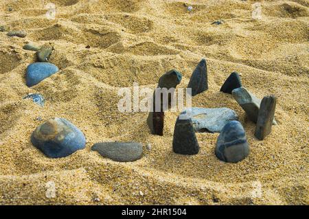 Mini-Stonehenge aus glatten Steinen an einem gelben Sandstrand Stockfoto