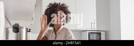 Lächelnde junge Frau, die in der Küche Tee in eine Tasse gießt Stockfoto