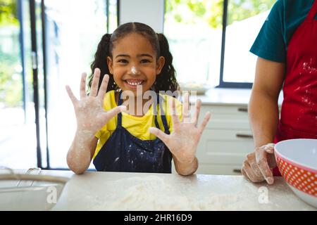 Portrait von glücklichen niedlichen Biracial Mädchen zeigt chaotische Hände in Mehl vom Vater in der Küche bedeckt Stockfoto