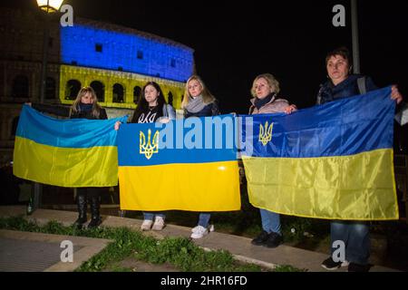 Rom Roma, Italien Italia. 24.. Februar 2022. Rom, 24.. Februar 2022. Die ukrainische Flagge wurde auf die Wände des Kolosseums in Rom projiziert, wo sich Menschen aus der ukrainischen Gemeinschaft versammelten, um ihre Fahnen zu schwingen, um gegen den Krieg gegen die Ukraine zu protestieren, der heute Morgen vom russischen Präsidenten Wladimir Putin erklärt wurde. Kredit: LSF Foto/Alamy Live Nachrichten Stockfoto