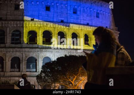 Rom Roma, Italien Italia. 24.. Februar 2022. Rom, 24.. Februar 2022. Die ukrainische Flagge wurde auf die Wände des Kolosseums in Rom projiziert, wo sich Menschen aus der ukrainischen Gemeinschaft versammelten, um ihre Fahnen zu schwingen, um gegen den Krieg gegen die Ukraine zu protestieren, der heute Morgen vom russischen Präsidenten Wladimir Putin erklärt wurde. Kredit: LSF Foto/Alamy Live Nachrichten Stockfoto