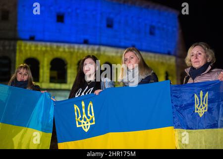 Rom Roma, Italien Italia. 24.. Februar 2022. Rom, 24.. Februar 2022. Die ukrainische Flagge wurde auf die Wände des Kolosseums in Rom projiziert, wo sich Menschen aus der ukrainischen Gemeinschaft versammelten, um ihre Fahnen zu schwingen, um gegen den Krieg gegen die Ukraine zu protestieren, der heute Morgen vom russischen Präsidenten Wladimir Putin erklärt wurde. Kredit: LSF Foto/Alamy Live Nachrichten Stockfoto