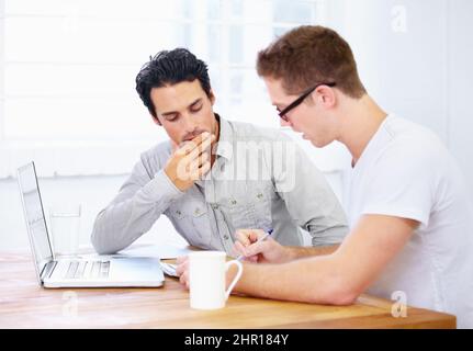 Geht über Designpunkte. Aufnahme von zwei jungen Geschäftsleuten, die sich über einen Laptop unterhalten. Stockfoto