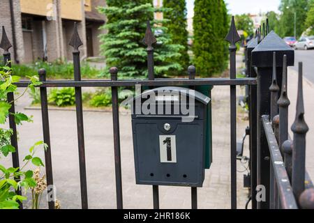 Briefkasten eines Privathauses, ein schwarzer Metallkasten, der auf dem Zaun eines Hauses installiert ist. Stockfoto