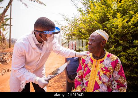 Ein afrikanischer Arzt besucht einen älteren Patienten und unterhält sich während der medizinischen Untersuchung. Health Care in africa Konzept Stockfoto