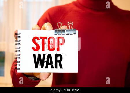 Die Phrase Stop war und Stop-Zeichen auf einem Karton-Banner in der Hand gezeichnet. Ein Mädchen hält einen Karton mit einer Inschrift. Mädchen auf der Straße. Protest, märz. Stockfoto