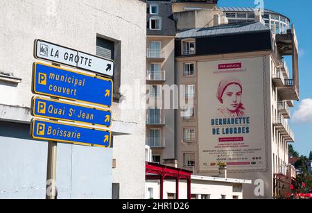 Lourdes, Frankreich - 28. August 2021: Schilder, die die Richtung der Erscheinungsgrotte in Lourdes und der Parkplätze anzeigen. Stockfoto