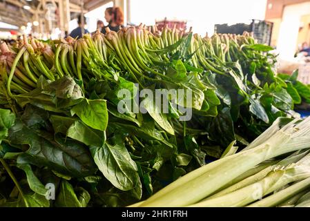 Frischer grüner Spinat zum Verkauf auf dem Gemüsemarkt, Nahaufnahme. Boxen voller Spinat im Laden. Spinat am Gemüsehändler. Beta-Anlage. Gemüse. Stockfoto