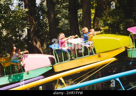 Die glücklichen Kinder auf einer Achterbahn im Vergnügungspark Stockfoto