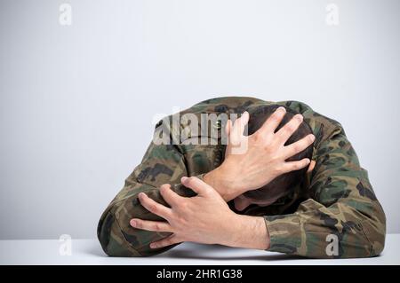 Obdachloser männlicher Soldat, der Drogen- und alkoholsüchtig war, allein sitzend und deprimiert und sich zu Hause ängstlich und allein fühlte. Stockfoto