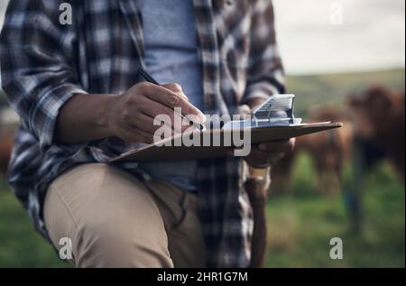 Arbeiten Sie nicht gegen die Natur, arbeiten Sie mit ihr. Aufnahme eines nicht erkennbaren Mannes, der Notizen schrieb, während er auf einer Kuhfarm arbeitete. Stockfoto