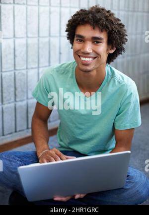 Ich habe ein Klassenzimmer in meiner Hand. Ein hübscher junger ethnischer Student, der mit seinem Laptop sitzt. Stockfoto