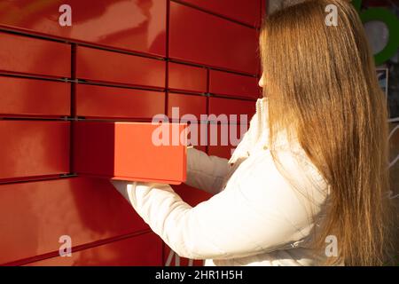 Frau holt Parsel vom automatisierten Postterminal ab Stockfoto