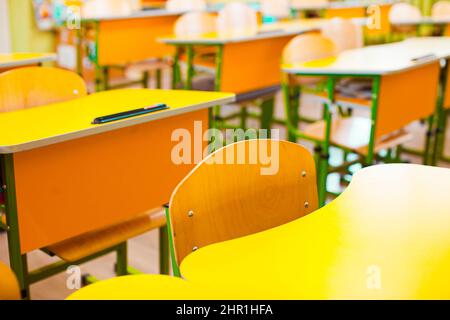 Stühle und Schreibtische in einem verlassenen Klassenzimmer in einer Schule Stockfoto