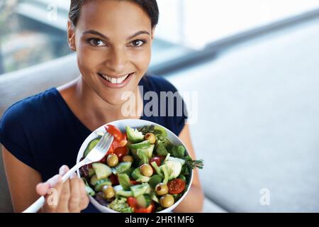 Eine ausgewogene Ernährung ist so wichtig. Draufsicht auf eine schöne junge Frau, die einen gesunden Salat in ihrem Haus genießt. Stockfoto