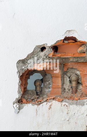 Gebrochene weiße Mauer mit freiliegenden Ziegelsteinen in einem Gebäude in Rio de Janeiro, Brasilien. Stockfoto