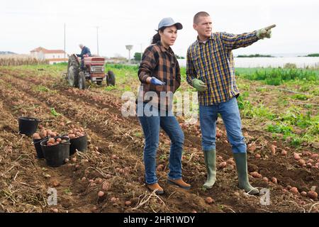 Zwei Landarbeiter auf einem Feld zeigen auf etwas Stockfoto