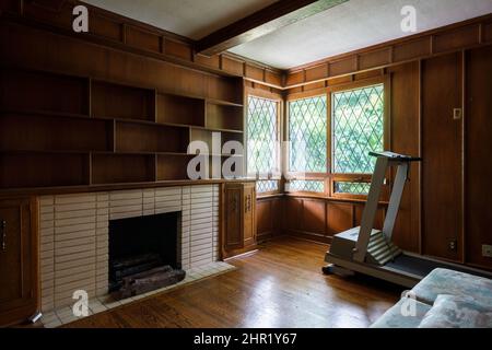 Ein Arbeitszimmer mit einem gemauerten Kamin, Bleifenstern, Holzwänden und Einbauten. Dieses Haus wurde abgerissen. Stockfoto