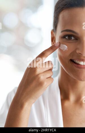 Ihre tägliche Hautpflegeroutine. Nahaufnahme Porträt einer wunderschönen jungen Frau mit Feuchtigkeitscreme auf ihre Haut. Stockfoto
