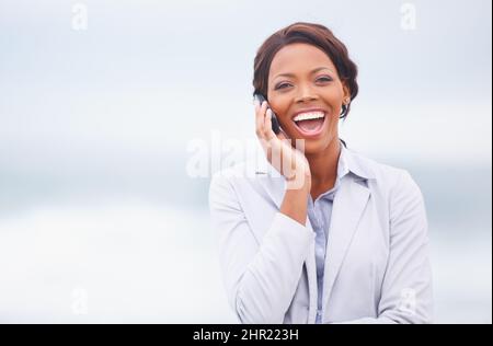 Lachen in der Meeresbrise. Eine hübsche afroamerikanische Frau, die im Freien ein angenehmes Gespräch führt. Stockfoto