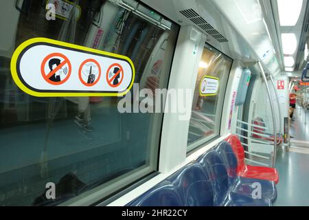 Aufkleber einer maskierten Person mit Zeigefinger über dem Mund und „kein Sprechen auf dem Telefon/mit Masken“-Hinweisen im Subway-Zugabteil von Singapur Stockfoto