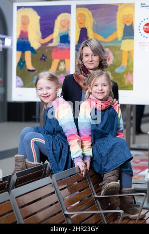 18. Februar 2022, Sachsen, Dresden: Emma (l.) und Lotte sitzen in einer Ausstellung zum Tag der Seltenen Erkrankungen vor dem Selbstporträt ihrer Mutter Katja Franke im Dresdner Hauptbahnhof. Die Zwillinge leiden an einer Neurofibromatose vom Typ 1, einer unheilbaren Krankheit. Mehr als vier Millionen Menschen in Deutschland leiden an einer von mehr als 6.000 Krankheiten, die nur sehr wenige andere haben. Der Welttag der Seltenen Krankheiten erinnert an die Sorgen der Betroffenen am 28. Februar 2022. Foto: Sebastian Kahnert/dpa-Zentralbild/dpa - ACHTUNG: Nur für redaktionelle Verwendung im Zusammenhang mit der aktuellen Berichterstattung über die Seltene Krankheiten Da Stockfoto