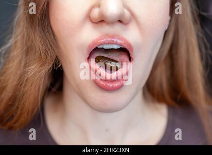 Pille auf ihrer Zunge. Nahaufnahme einer jungen Frau, die die Pille auf ihrer Zunge hält. Schöne Frau Mund Mit Pille Auf Der Zunge. Mädchen Nimmt Medizin Stockfoto