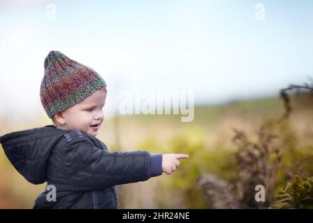 Von der Natur her. Ein süßer kleiner Junge, der draußen auf etwas zeigt. Stockfoto