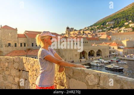 Frau mit Blick auf alten mittelalterlichen Hafen auf den oberen Mauern der Stadt Dubrovnik in Kroatien. Dubrovnik historische Stadt von Kroatien in Dalmatien. UNESCO Venetian Stockfoto