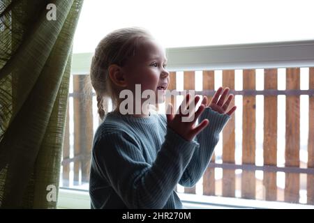 Kleine niedliche Mädchen klatschen ihre Hände sitzen am großen Fenster Stockfoto