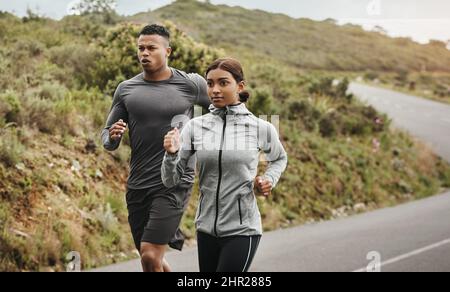 Halten Sie nicht an, bis Sie das Ende erreicht haben. Aufnahme zweier sportlicher junger Menschen, die im Freien laufen. Stockfoto