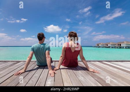Paare verbringen einen romantischen Strandurlaub in einem luxuriösen Resort auf den Malediven mit türkisfarbenem Meerwasser, blauem Himmel und Überwasser-Villen auf wo Stockfoto