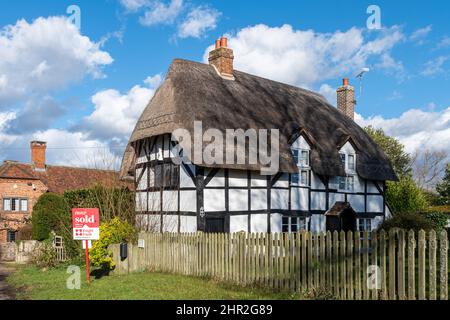 Hübsches ländliches Reethaus in Froyle Village mit Sold Sign, Hampshire, England, UK Stockfoto