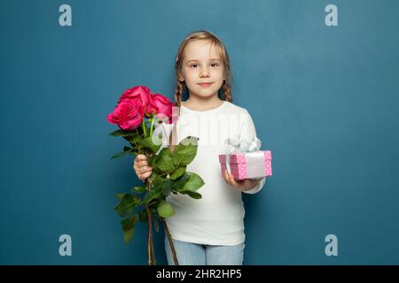 Kleine Tochter Kind Mädchen mit rosa Blumen Rose und Geschenkbox. 8 märz Karte oder Muttertag Konzept Stockfoto