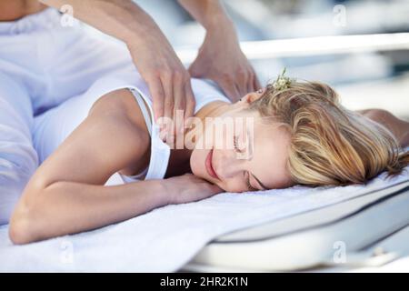 Genießen Sie eine tolle Massage. Junge Frau erhält eine entspannende Massage. Stockfoto