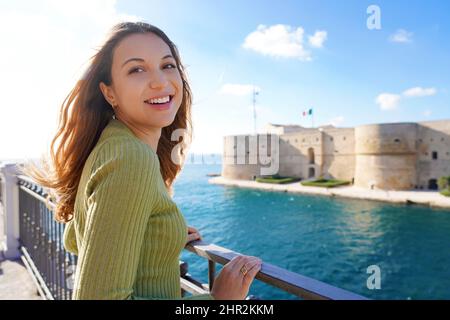 Porträt einer lächelnden, entspannten Frau, die mit Taranto-Strand im Hintergrund die Kamera anschaut, Apulien, Italien Stockfoto