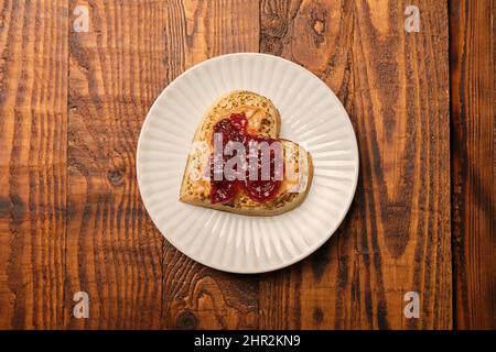 Ein herzförmiges Krustentier mit Erdnussbutter und Gelee-Marmelade. Stockfoto