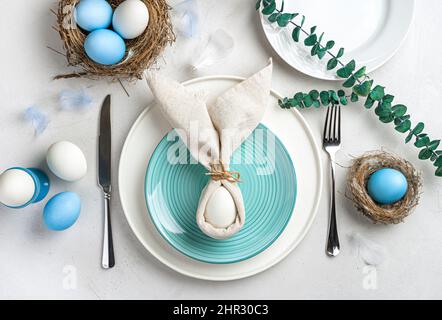 Servieren des Osterfesttags-Tisches. Osterhase aus Eiern und Servietten auf einem Teller. Stockfoto