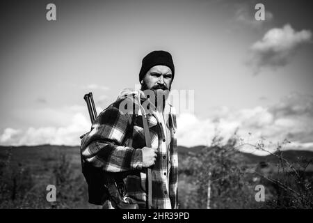 Jäger mit Schrotflinte auf der Jagd. Bärtiger Jäger mit Waffe und Spaziergang im Wald. Herbst. Stockfoto