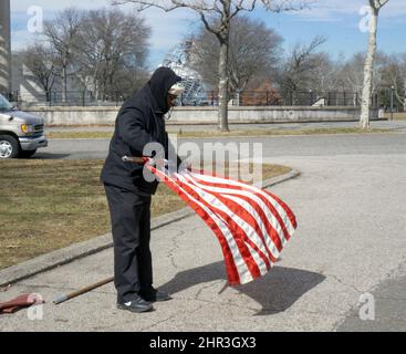 Nach einem katholischen Gottesdienst im Freien rollt ein Gläubiger die amerikanische Flagge hoch. In einem Park in Queens, New York City, in der Nähe eines Vatikanischen Pavillons. Stockfoto