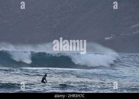 Surferin, große Wellen nähern sich der Küste in Puerto de la Cruz Teneriffa Kanarische Inseln Spanien. Stockfoto