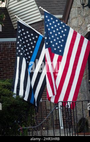 Ein Haus mit einer amerikanischen Standardflagge und einer dünnen blauen Linie einer amerikanischen Flagge, die die Unterstützung der Polizei symbolisiert. Stockfoto