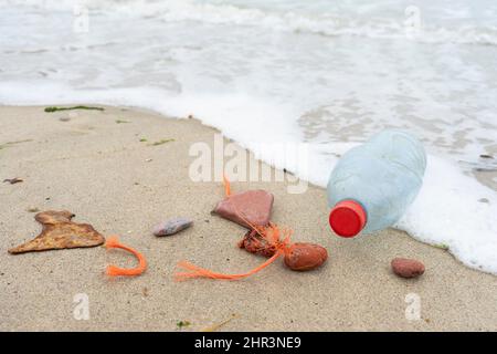 Plastiksuppe Abwasserflasche in den Wellen am Ufer eines leeren Strandes gewaschen Stockfoto