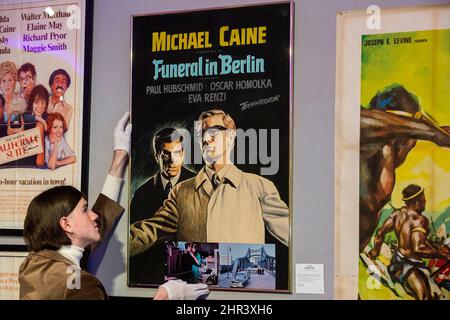 London, Großbritannien. 25. Februar 2022. Ein Mitarbeiter hängt ikonische Filmplakate an einer Vorschau für den Verkauf von wertvollen Besitztümern aus der persönlichen Sammlung des Schauspielers Sir Michael Caine. Am 2. März werden in der Bonhams New Bond Street Gegenstände von Filmplakaten bis hin zu Kunstwerken angeboten, die die gesamte Bandbreite seiner Karriere abdecken. Kredit: Stephen Chung / Alamy Live Nachrichten Stockfoto