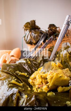 Ein traditionelles kolumbianisches Essen, bekannt als „Tamales“, das mit Blättern in einem Korb verpackt ist Stockfoto