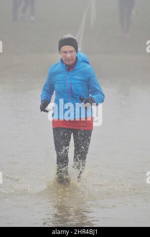 Rentnerinnen laufen Club Cross Country Rennen durch Wasser Gefahr Stockfoto