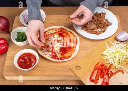 Hinzufügen von Fleischstücken zu den Reihen von Kohl und Zwiebeln. Kochen von Kebab zu Hause. Stockfoto